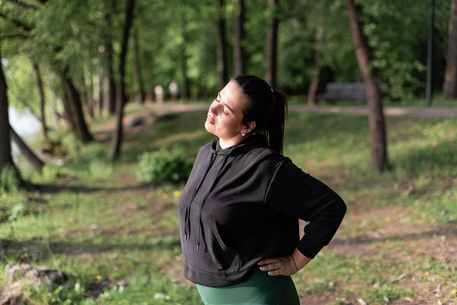 A woman stretching in a sunny park